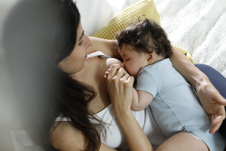 Maman allaitant son bébé et lui tenant la main